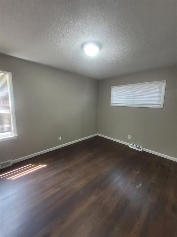 spare room featuring dark hardwood / wood-style flooring and a textured ceiling