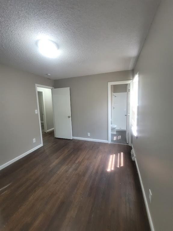 unfurnished room with dark hardwood / wood-style flooring and a textured ceiling