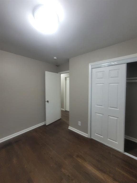 unfurnished bedroom with dark hardwood / wood-style flooring and a closet