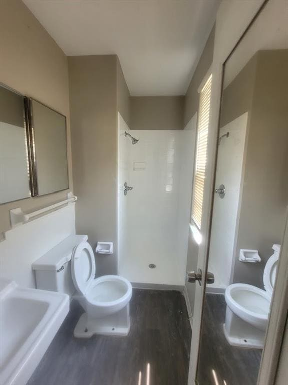 bathroom featuring hardwood / wood-style flooring, toilet, and a shower