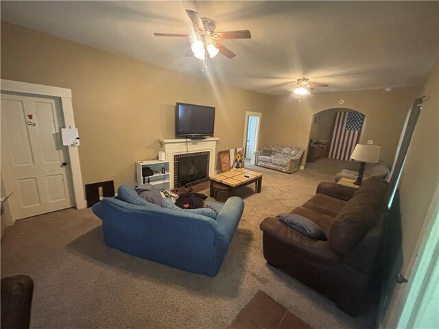 living room featuring ceiling fan, a fireplace, and carpet