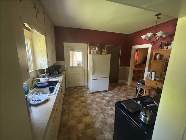 kitchen featuring sink, white cabinets, a chandelier, white refrigerator, and hanging light fixtures