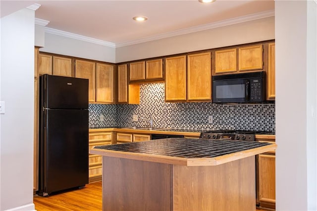 kitchen featuring brown cabinets, crown molding, light wood finished floors, tasteful backsplash, and black appliances