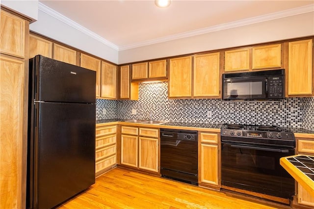 kitchen featuring light wood finished floors, decorative backsplash, ornamental molding, a sink, and black appliances