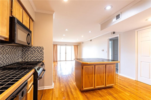 kitchen featuring visible vents, tile counters, black appliances, tasteful backsplash, and crown molding