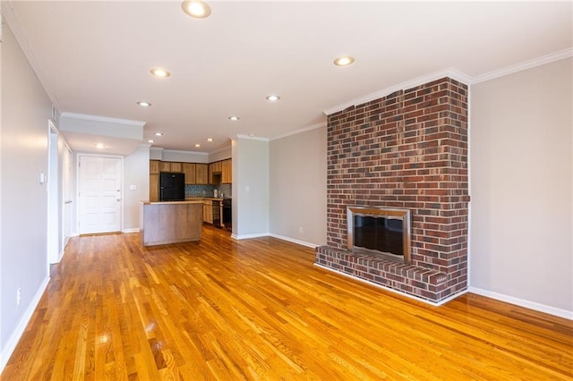 unfurnished living room with light wood-type flooring, a fireplace, and crown molding