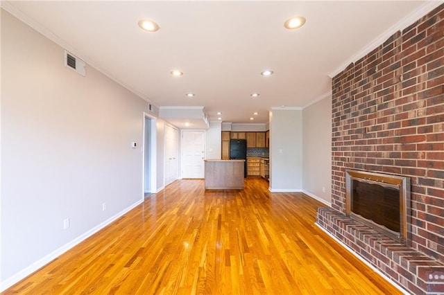 unfurnished living room featuring ornamental molding, light wood-type flooring, a fireplace, and baseboards