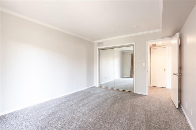 unfurnished bedroom featuring carpet floors, crown molding, baseboards, and a closet