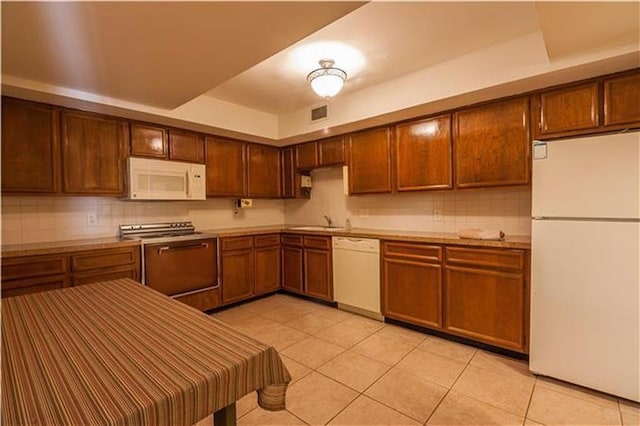 kitchen with white appliances, light countertops, backsplash, and light tile patterned floors