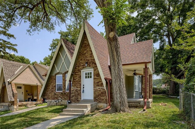 english style home with ceiling fan and a front yard