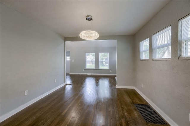 unfurnished dining area with a notable chandelier, plenty of natural light, and dark hardwood / wood-style floors