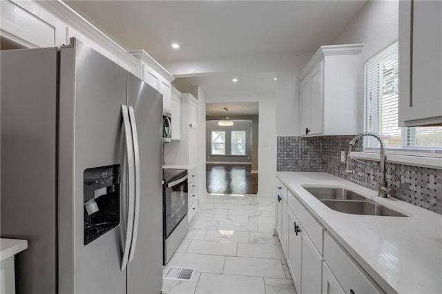 kitchen featuring sink, white cabinetry, backsplash, stainless steel appliances, and a wealth of natural light