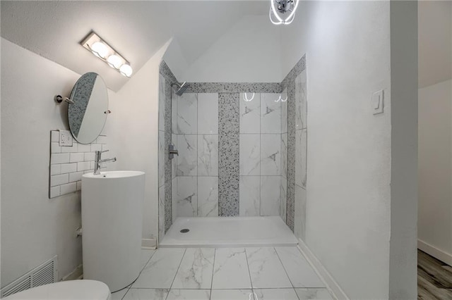 bathroom featuring a tile shower, vanity, and toilet