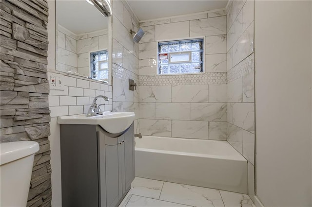 full bathroom with tiled shower / bath, vanity, and toilet