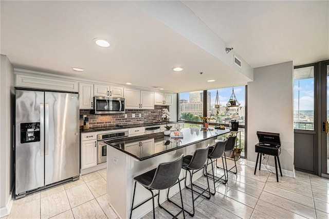 kitchen featuring appliances with stainless steel finishes, white cabinetry, a breakfast bar, and tasteful backsplash