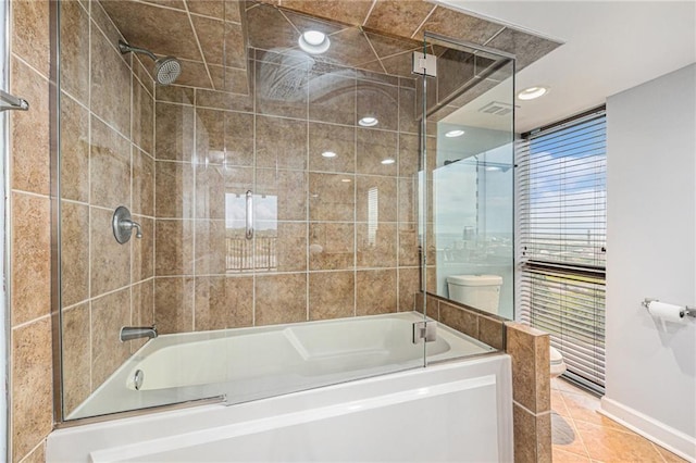 bathroom featuring enclosed tub / shower combo, toilet, and tile patterned flooring