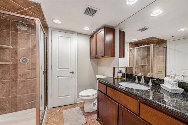 bathroom featuring tile patterned floors, vanity, a shower with shower door, and toilet