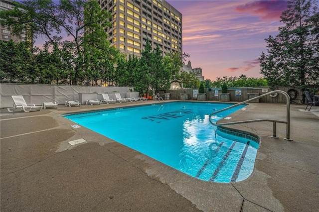 pool at dusk featuring a patio