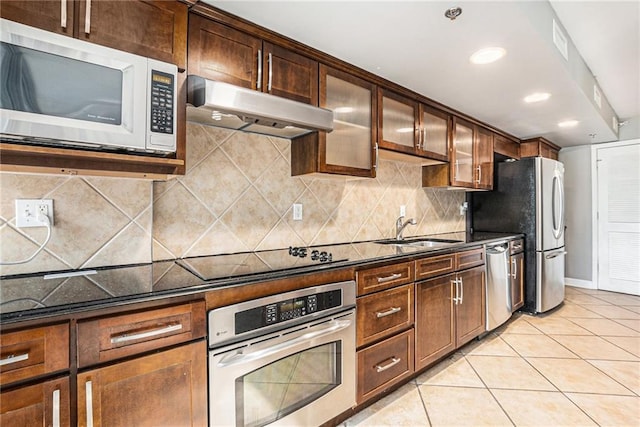 kitchen featuring dark stone countertops, light tile patterned floors, appliances with stainless steel finishes, sink, and tasteful backsplash