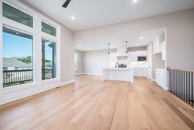 unfurnished living room featuring ceiling fan, plenty of natural light, and light hardwood / wood-style flooring