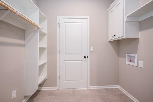 washroom featuring light tile patterned floors, hookup for a washing machine, and cabinets