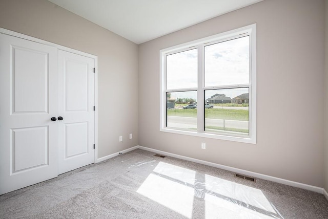 unfurnished bedroom featuring light colored carpet and a closet