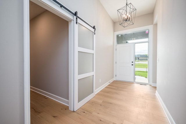 entrance foyer with a notable chandelier, light hardwood / wood-style flooring, and a barn door