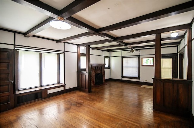 interior space featuring radiator heating unit, parquet floors, coffered ceiling, a brick fireplace, and beam ceiling