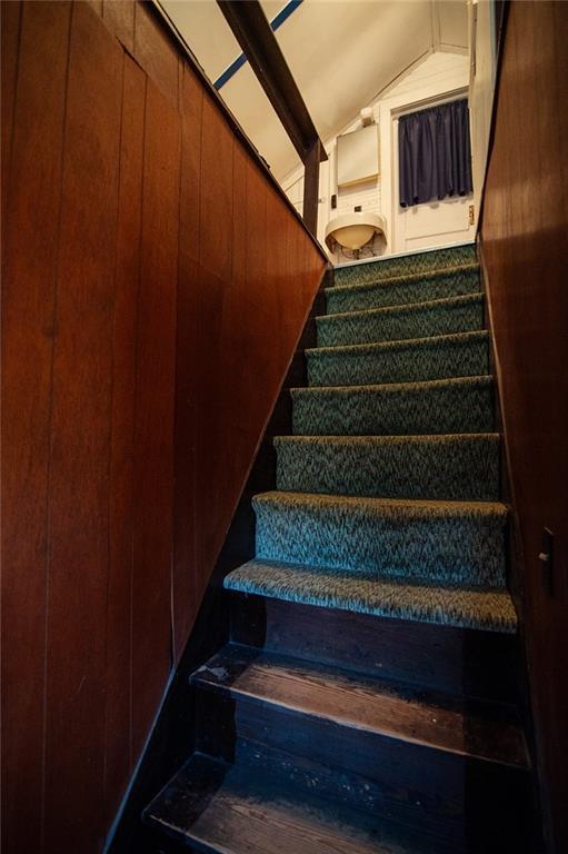 stairs with vaulted ceiling and wooden walls