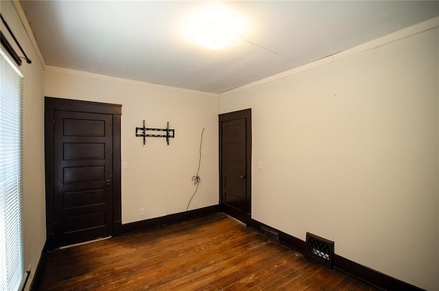 empty room featuring crown molding and dark wood-type flooring