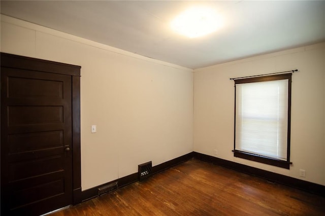 empty room with ornamental molding and dark hardwood / wood-style flooring