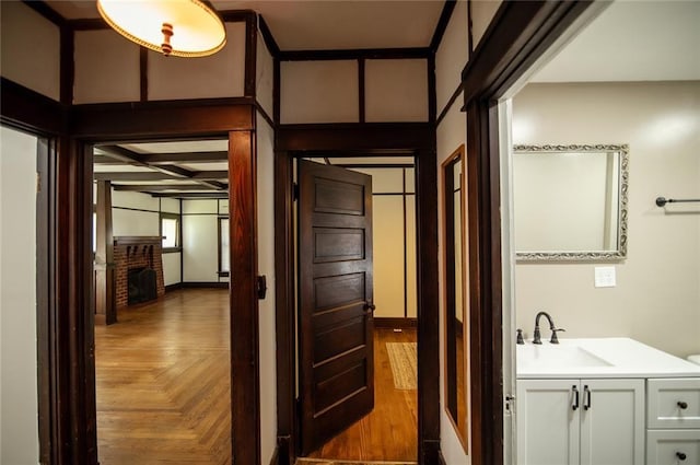 bathroom featuring vanity, a brick fireplace, parquet flooring, and coffered ceiling