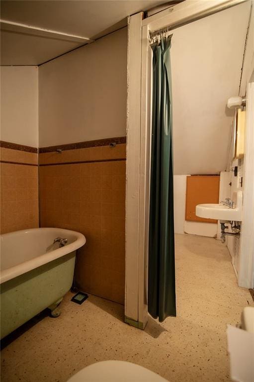 bathroom with a bathing tub, sink, and tile walls