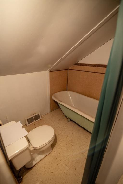 bathroom featuring toilet, lofted ceiling, and a bath