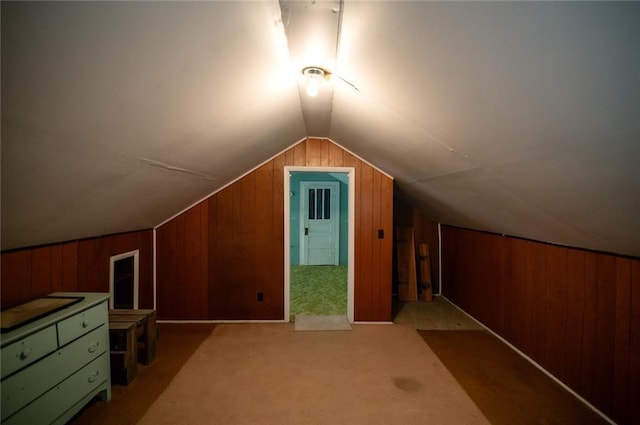 bonus room with light colored carpet, vaulted ceiling, and wood walls