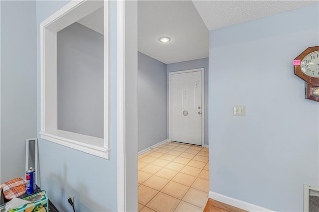 hall featuring a textured ceiling and light tile patterned flooring