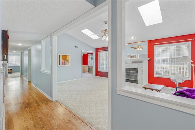 hallway featuring light hardwood / wood-style floors and lofted ceiling with skylight