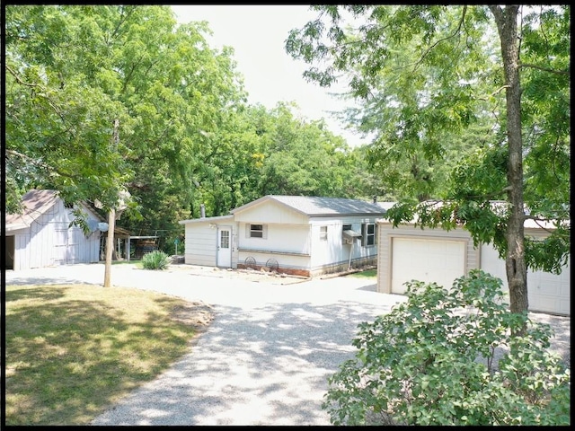 single story home featuring a garage, a front lawn, and an outdoor structure