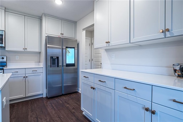 kitchen featuring dark wood-type flooring, stainless steel appliances, and a textured ceiling