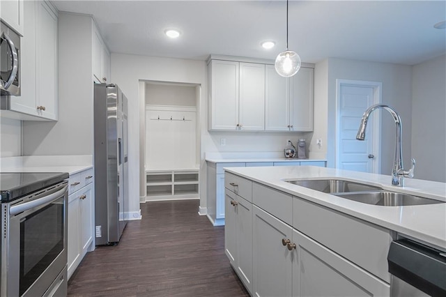 kitchen with white cabinets, hanging light fixtures, sink, appliances with stainless steel finishes, and dark hardwood / wood-style flooring