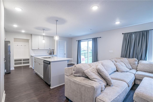 kitchen with decorative light fixtures, white cabinetry, stainless steel appliances, and an island with sink