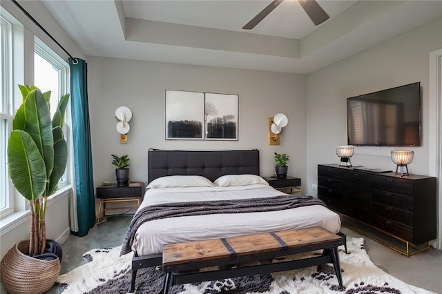 carpeted bedroom with ceiling fan and a raised ceiling