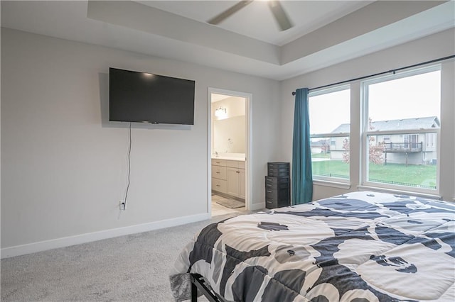 carpeted bedroom with ensuite bathroom, a raised ceiling, and ceiling fan