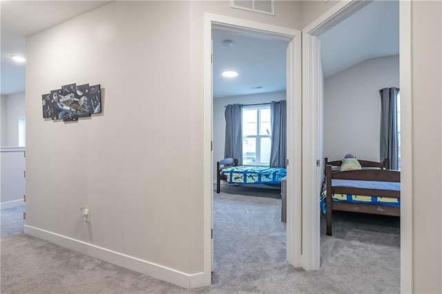 hallway featuring light colored carpet and vaulted ceiling