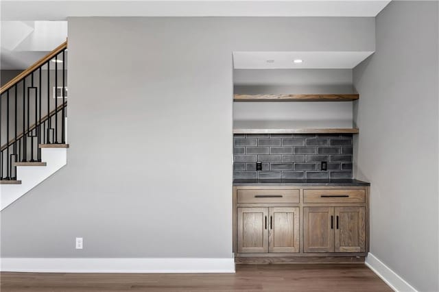 13709 Pembroke Ln, Leawood, KS 66224 - bar featuring stairway, wood finished floors, decorative backsplash, baseboards, and recessed lighting