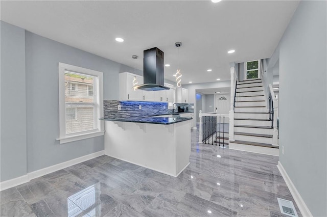 kitchen with a breakfast bar area, white cabinets, island exhaust hood, decorative light fixtures, and kitchen peninsula