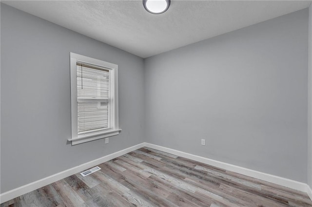 spare room featuring light hardwood / wood-style flooring and a textured ceiling