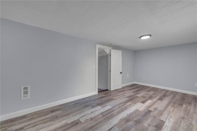 unfurnished room featuring a textured ceiling and light wood-type flooring