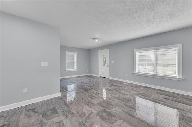 empty room with plenty of natural light and a textured ceiling