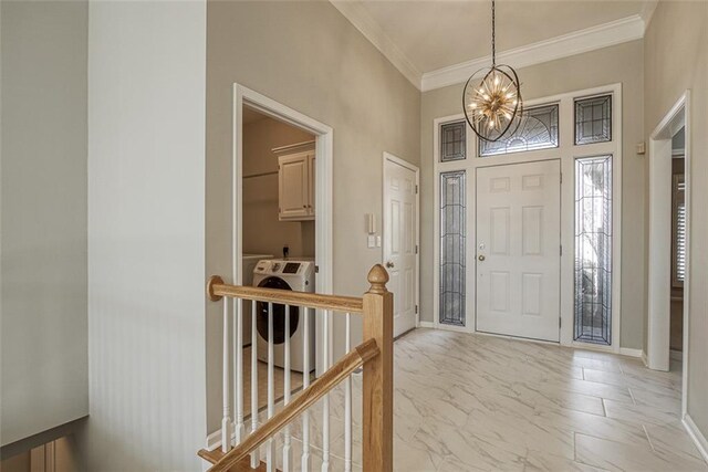 tiled entrance foyer with washing machine and clothes dryer, crown molding, and a chandelier